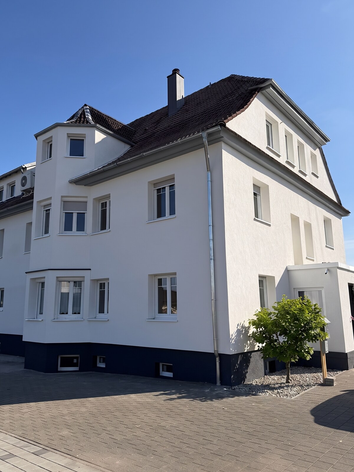 Saniertes Wohnhaus in Hugsweier: weiße Fassade, neue Fenster, gepflasterter Hof